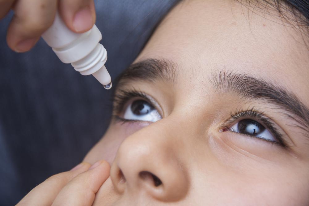 Primary school age girl puts eye drops into her eye.jpg