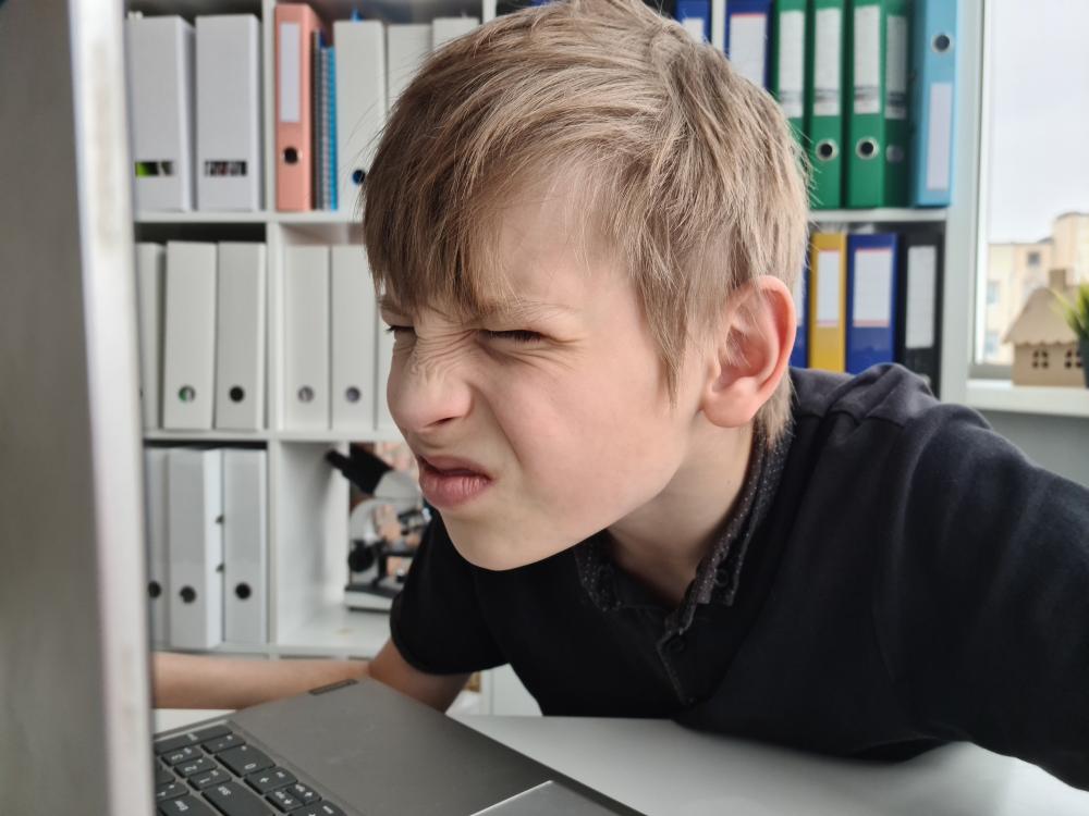Boy squinting eyes in front of laptop.jpg